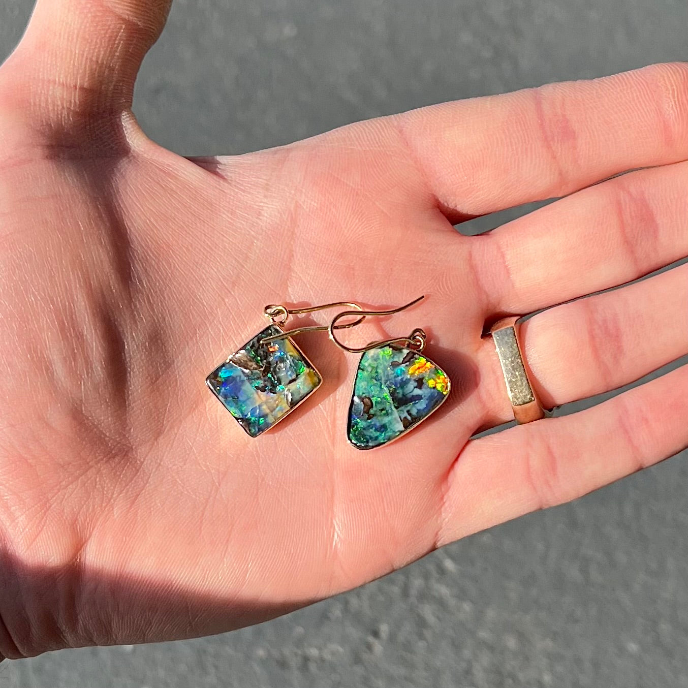 An asymmetric pair of French wire dangle yellow gold boulder opal earrings.  One opal is a square, and the other is a triangle.