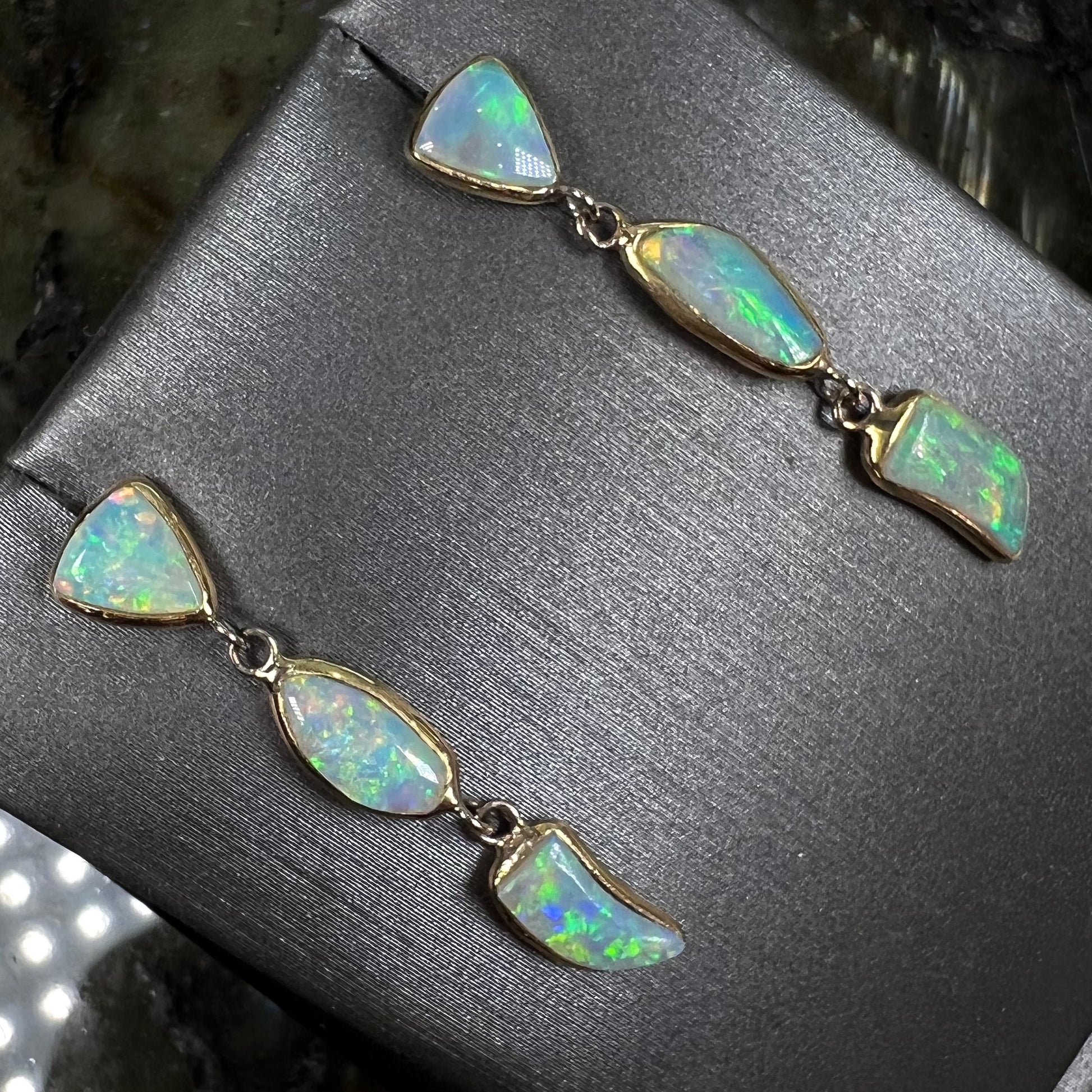 A pair of yellow gold push-back dangle earrings set with three white crystal opals in each.