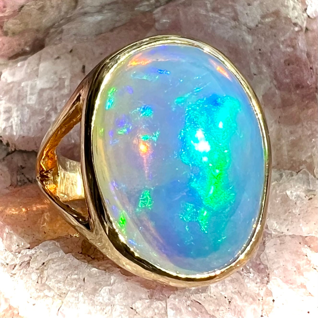 A gold split shank solitaire ring set with an oval cabochon cut 16.83 carat Ethiopian jelly fire opal.