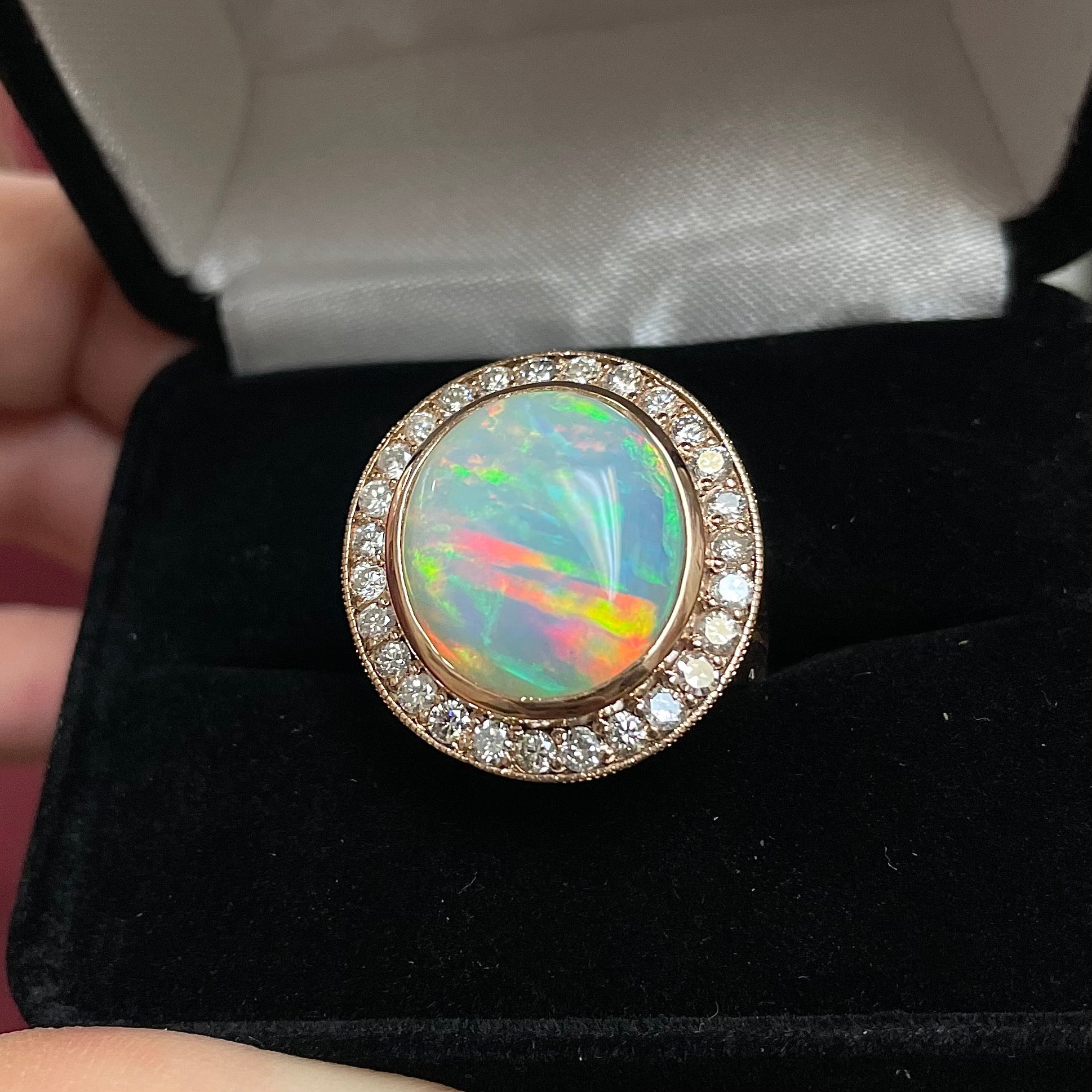 A large, Australian white crystal opal set in a rose gold and diamond halo ring.