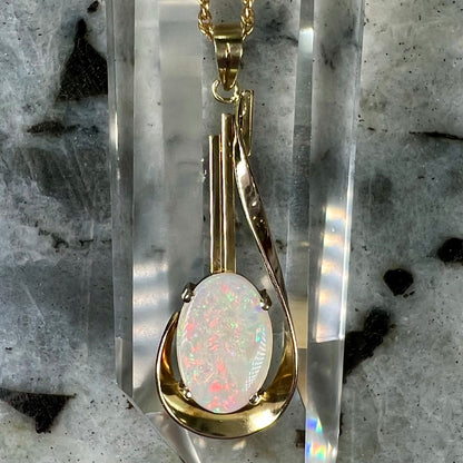 A handmade gold drop pendant set with an oval cabochon cut white crystal opal.