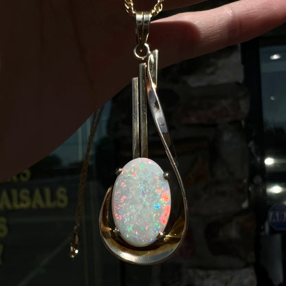 A handmade gold drop pendant set with an oval cabochon cut white crystal opal.