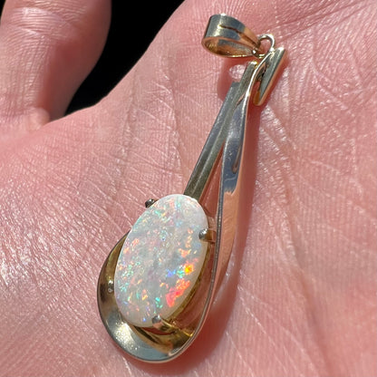 A handmade gold drop pendant set with an oval cabochon cut white crystal opal.