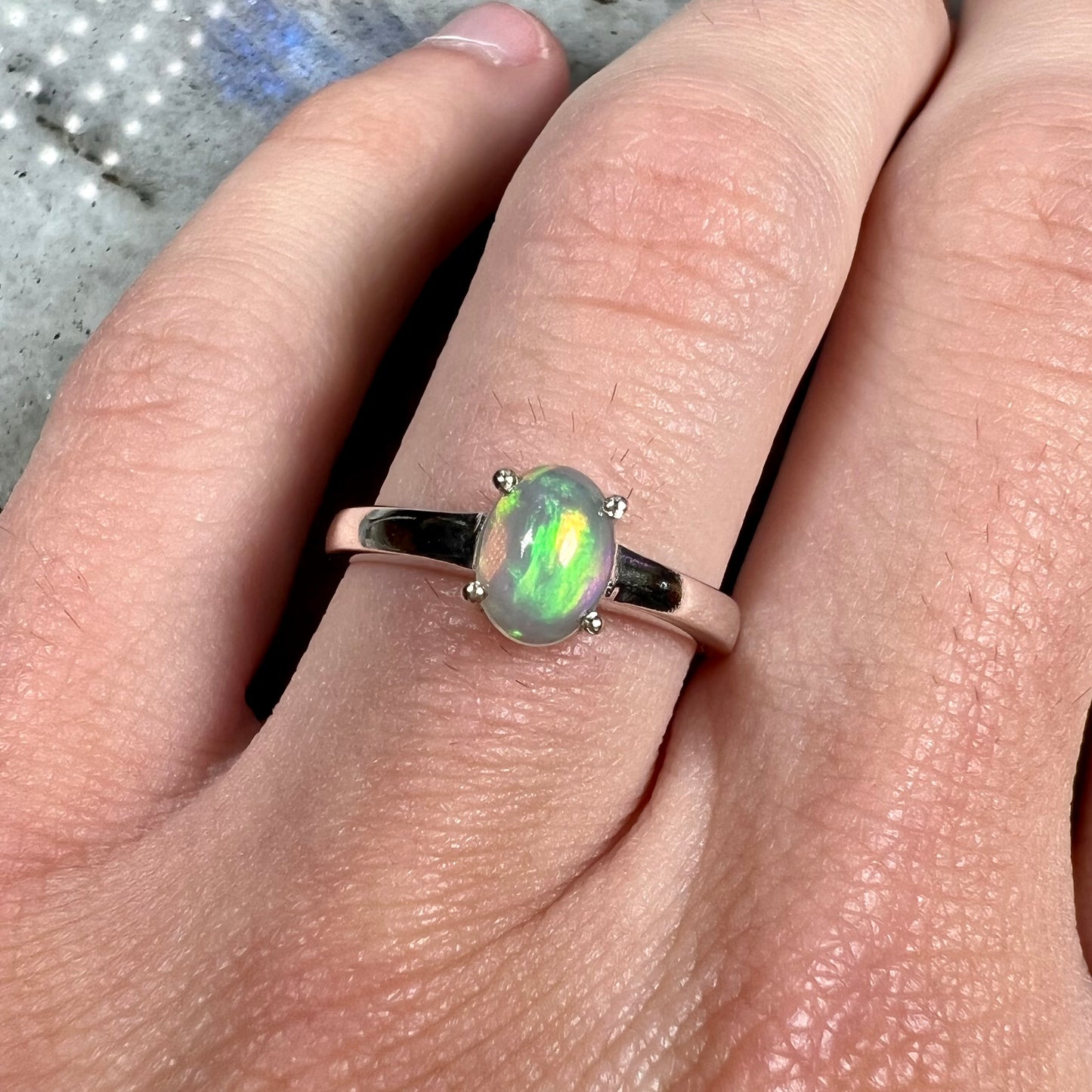 A silver, prong set, oval cabochon cut Ethiopian opal solitaire ring.