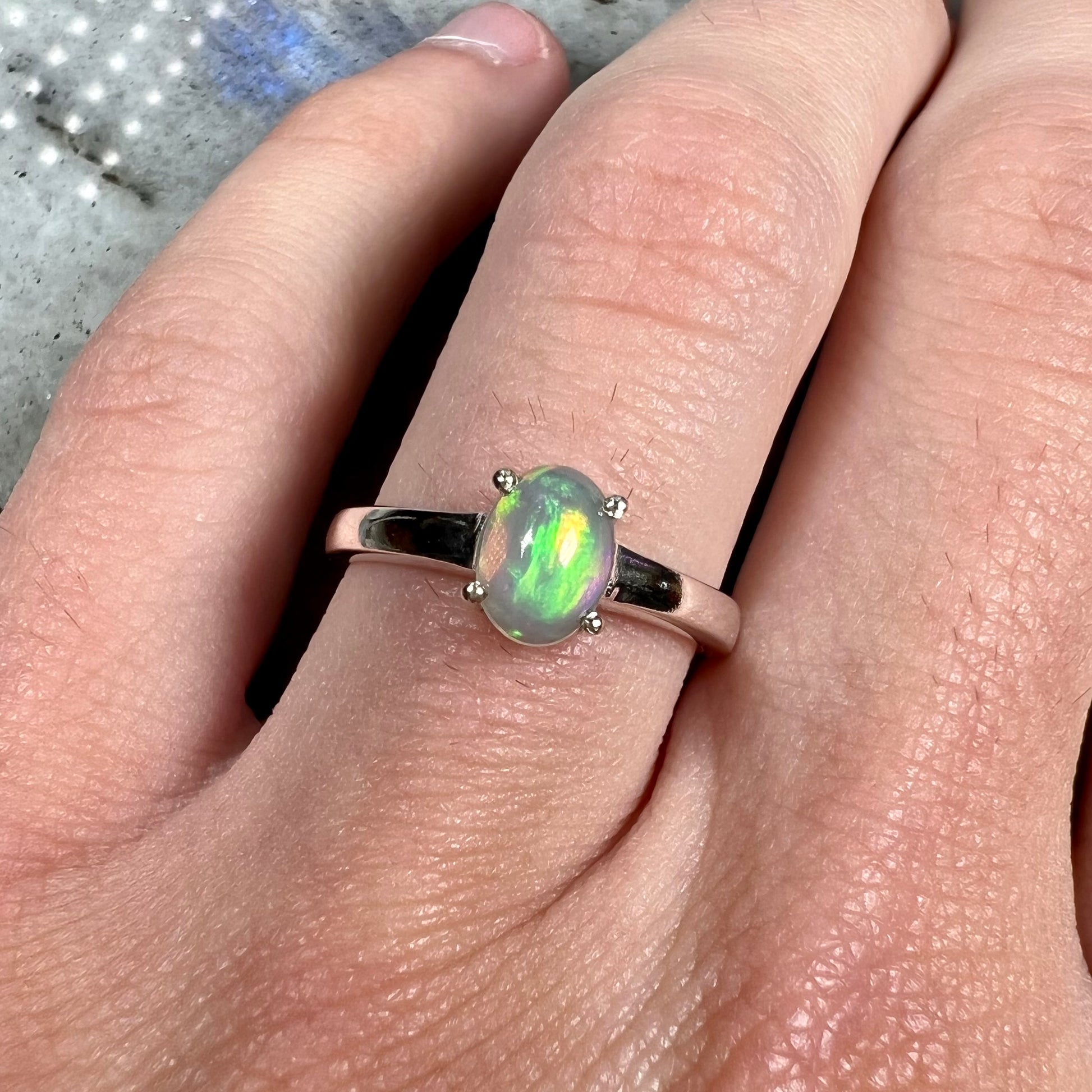 A silver, prong set, oval cabochon cut Ethiopian opal solitaire ring.