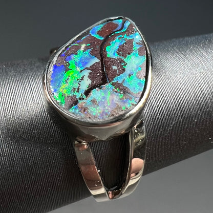 A split shank white gold boulder opal solitaire ring.  The stone has a natural hematite seam that runs through it.