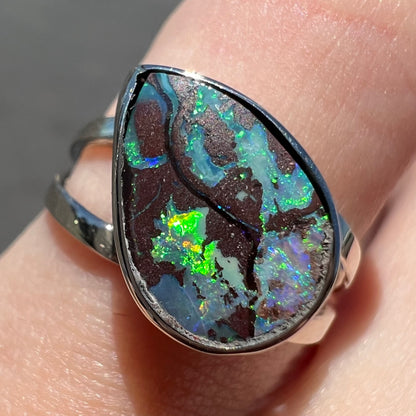 A split shank white gold boulder opal solitaire ring.  The stone has a natural hematite seam that runs through it.