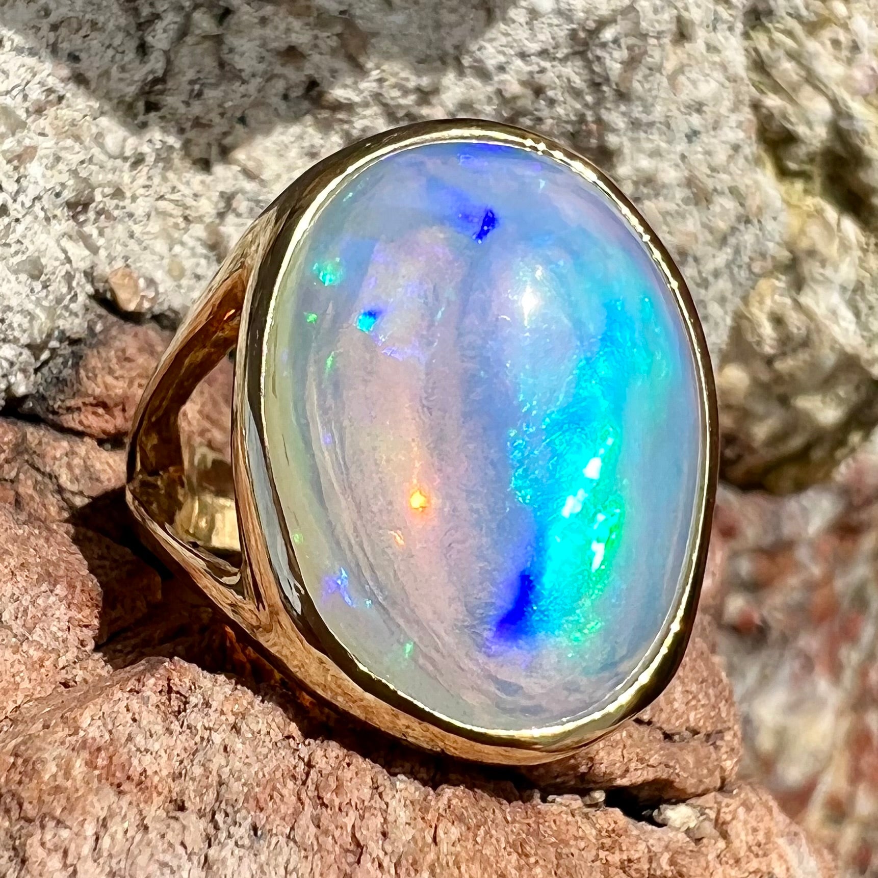 A gold split shank solitaire ring set with an oval cabochon cut 16.83 carat Ethiopian jelly fire opal.
