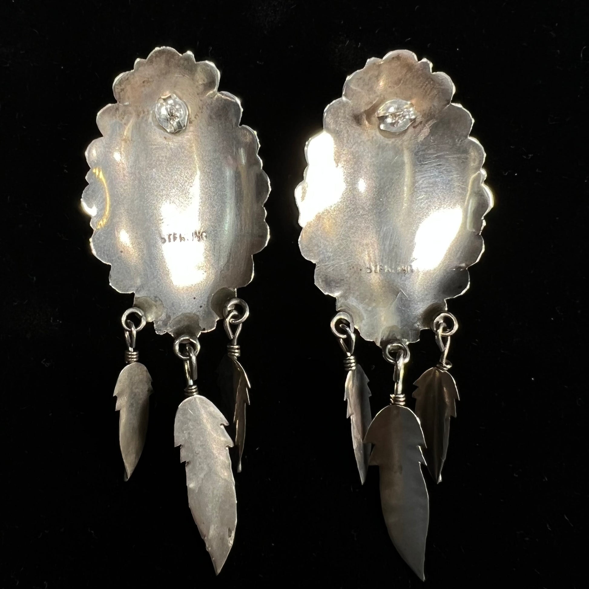 A pair of Native American style feather dangle earrings inlaid with mother of pearl shell and turquoise.