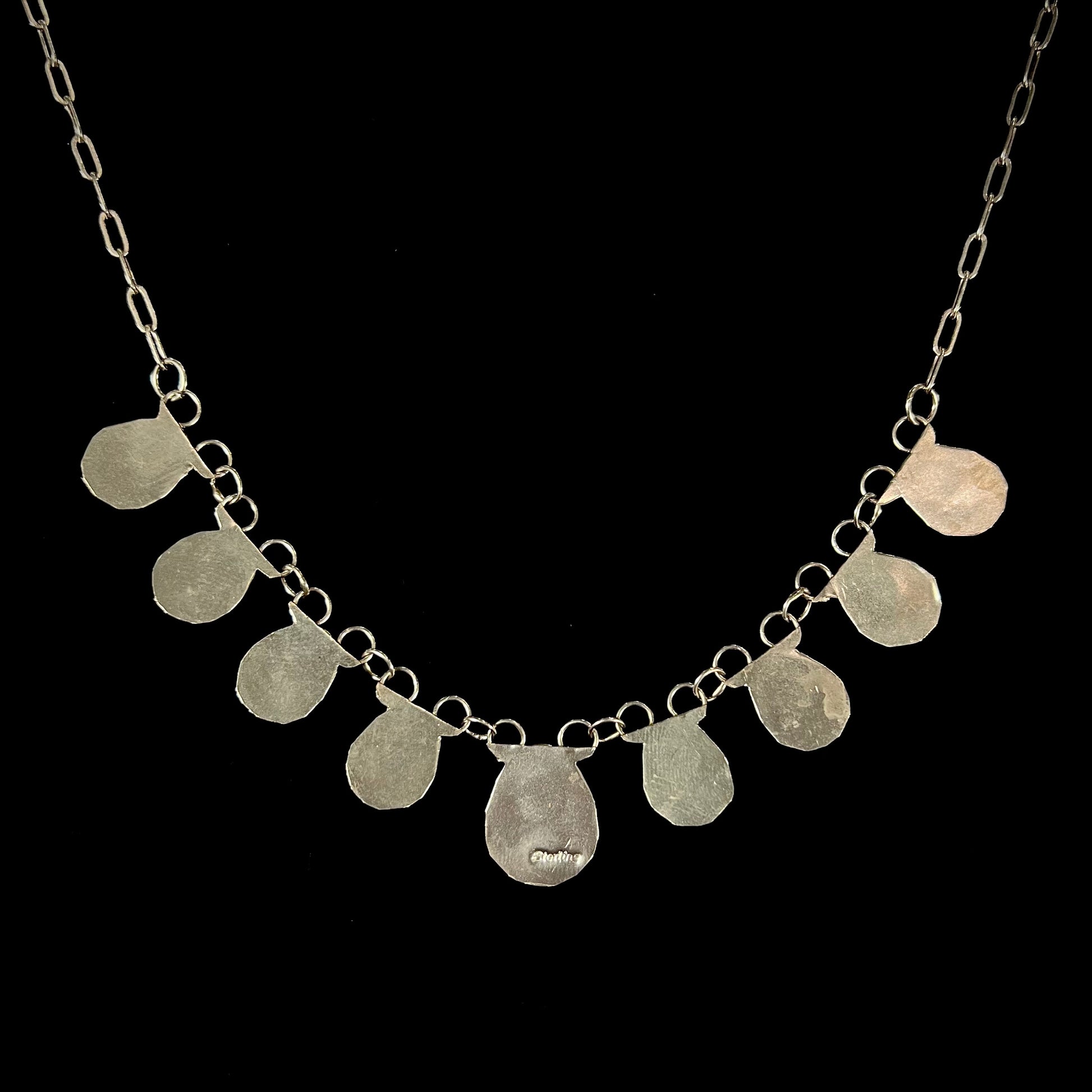 A silver turquoise necklace handmade with nine silver bear paws set with round turquoise stones.