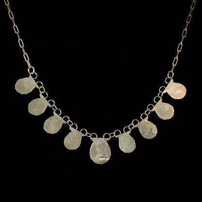 A silver turquoise necklace handmade with nine silver bear paws set with round turquoise stones.