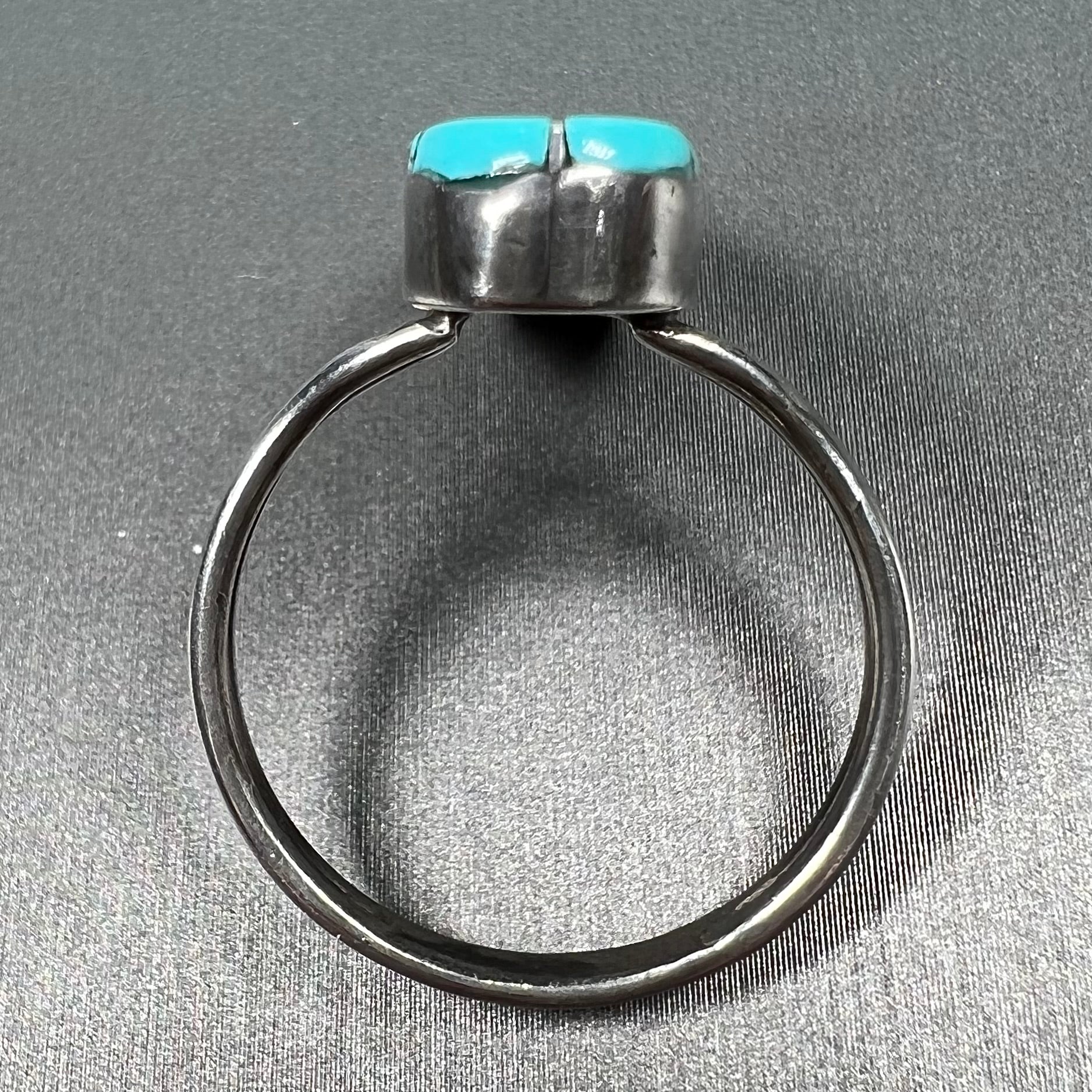 A handmade silver turquoise ring inlaid with six pieces of Sleeping Beauty turquoise.  The back of the ring is signed "FT".