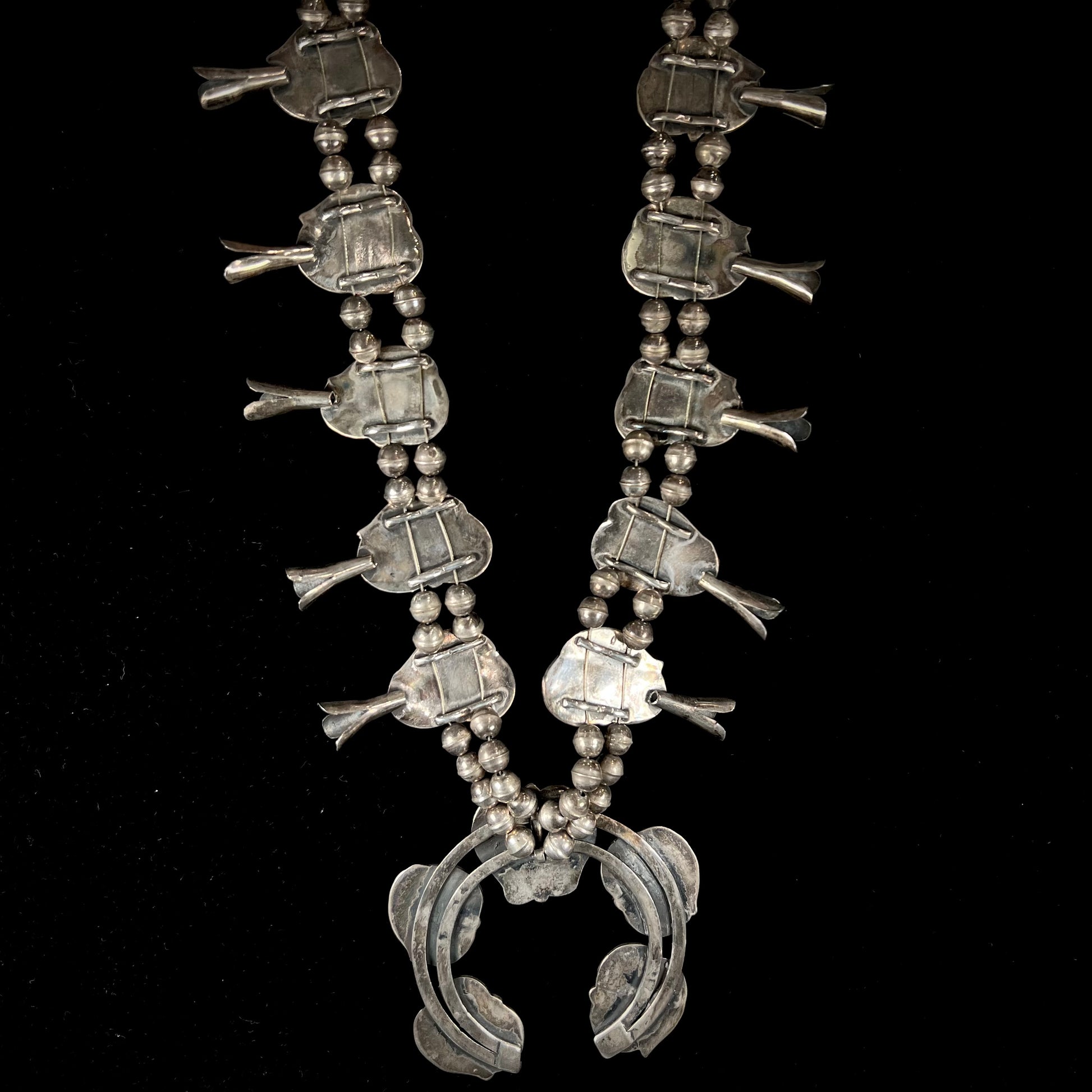 A handmade silver Navajo style squash blossom necklace set with green Kingman turquoise.
