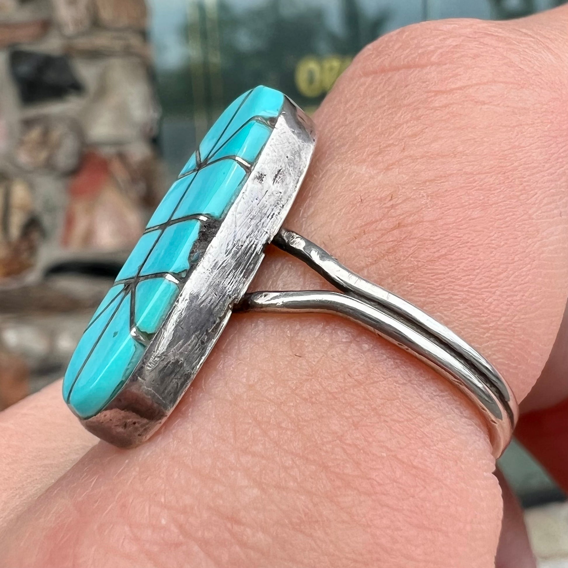 A handmade silver turquoise ring inlaid with six pieces of Sleeping Beauty turquoise.  The back of the ring is signed "FT".