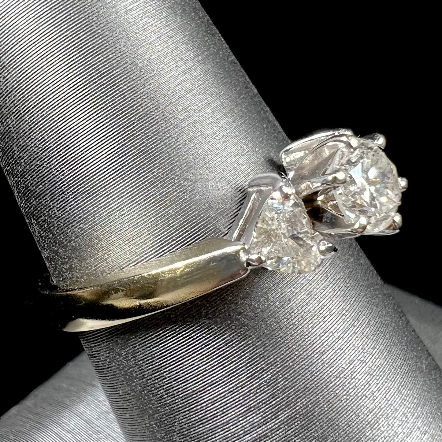 A ladies' three stone diamond ring.  The center diamond is a round brilliant cut, and the two accents are heart shaped diamonds.