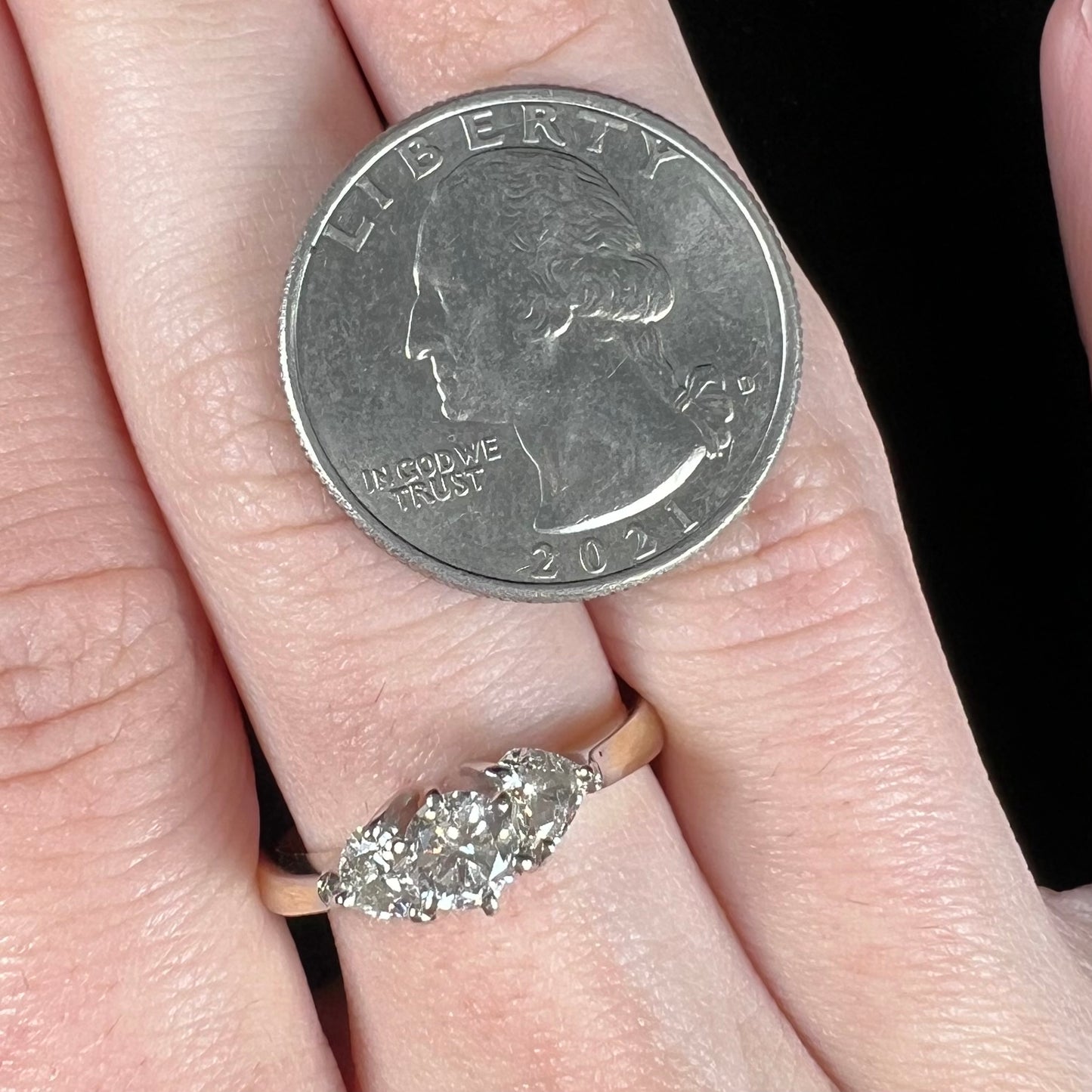 A ladies' three stone diamond ring.  The center diamond is a round brilliant cut, and the two accents are heart shaped diamonds.