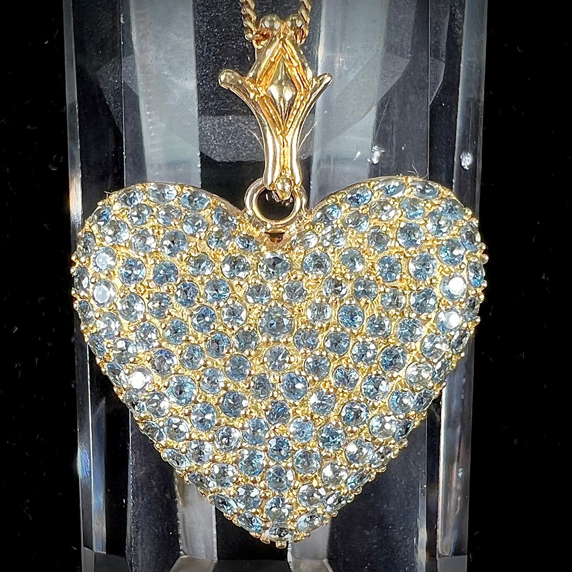 A gold heart pendant pave set with round aquamarine stones.