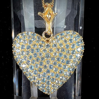 A gold heart pendant pave set with round aquamarine stones.