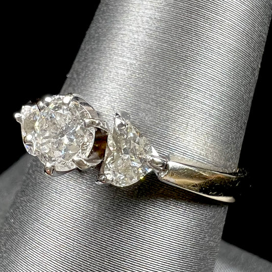 A ladies' three stone diamond ring.  The center diamond is a round brilliant cut, and the two accents are heart shaped diamonds.