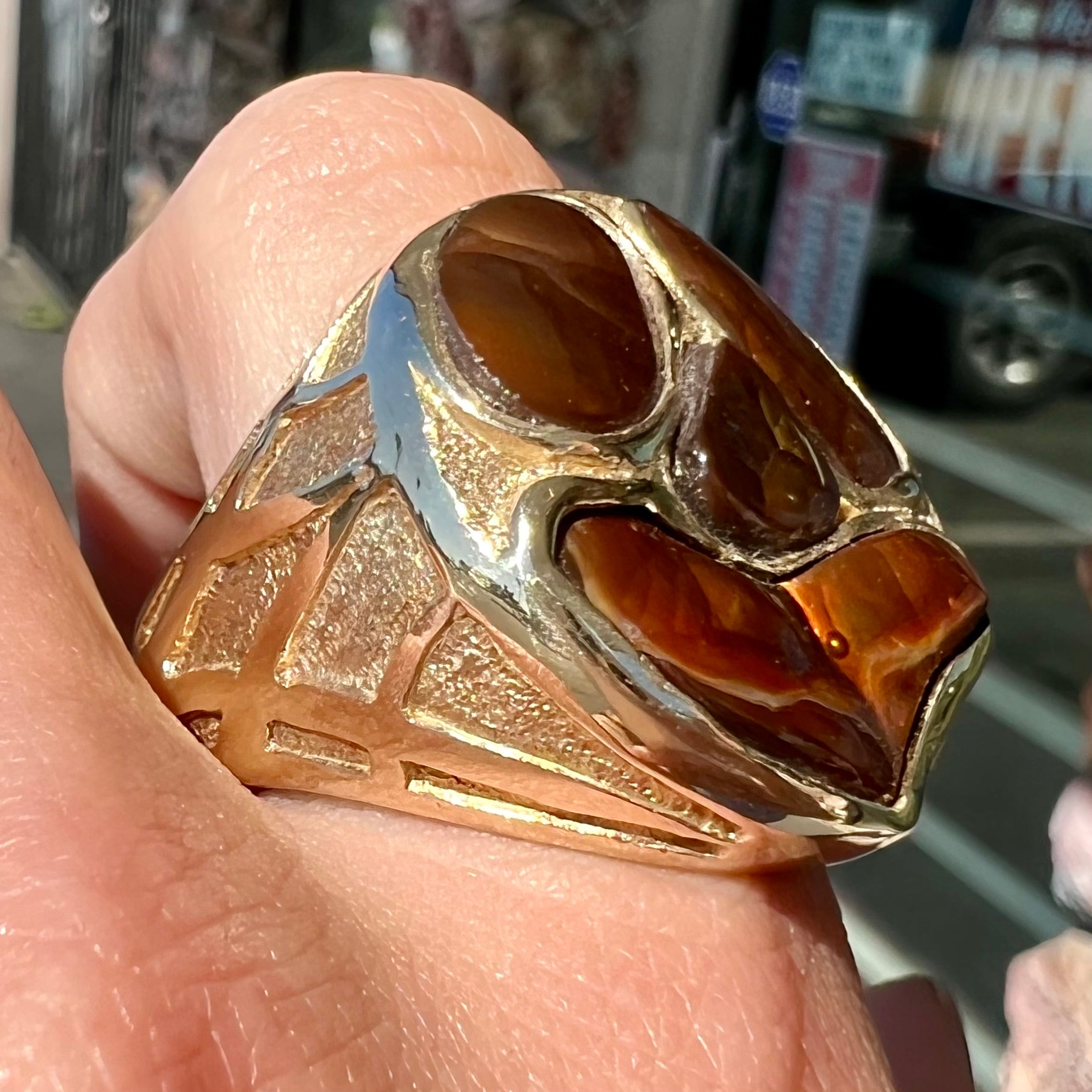 A yellow gold men's thug ring set with four fire agate stones resembling a spooky face.