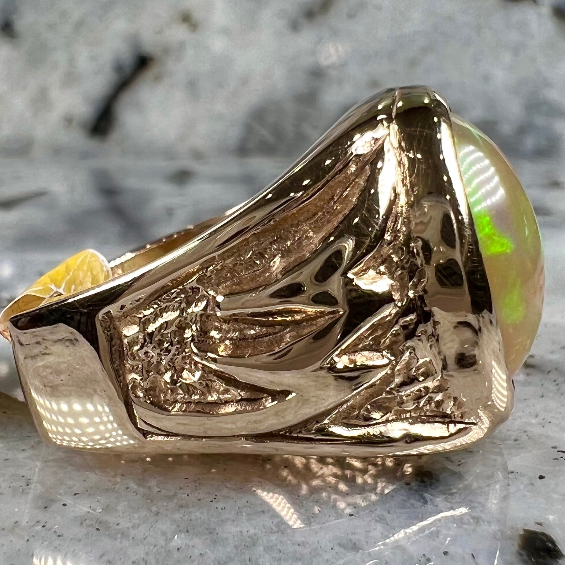A solid yellow gold solitaire men's fire opal ring.  The stone is an orange oval cabochon cut.
