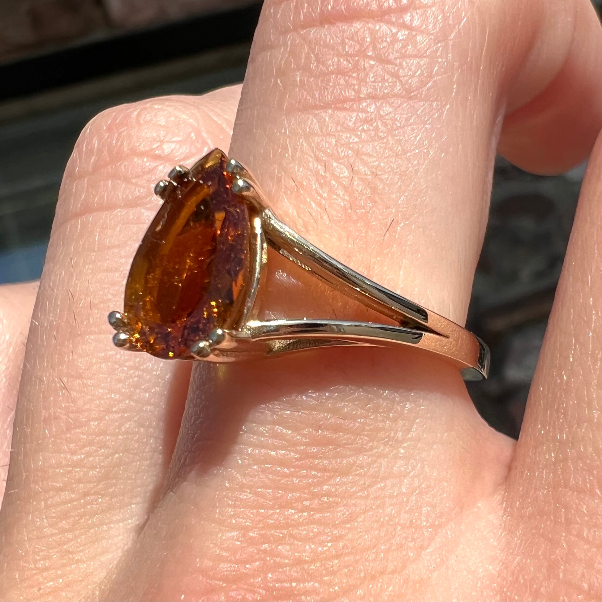 A gold split Euro shank solitaire ring set with an orange pear shape hessonite garnet stone.