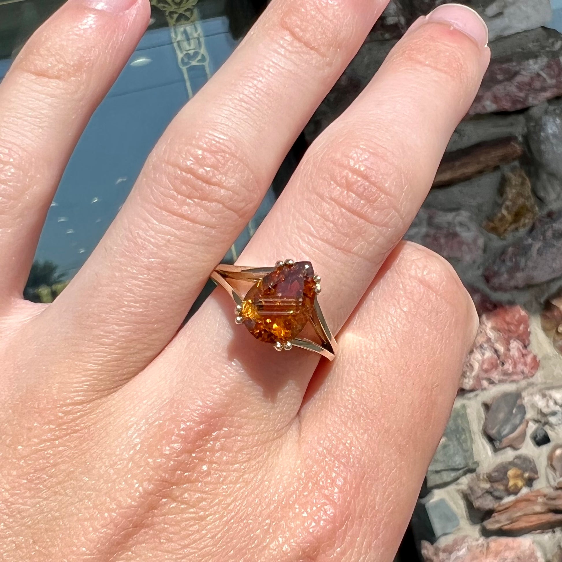 A gold split Euro shank solitaire ring set with an orange pear shape hessonite garnet stone.