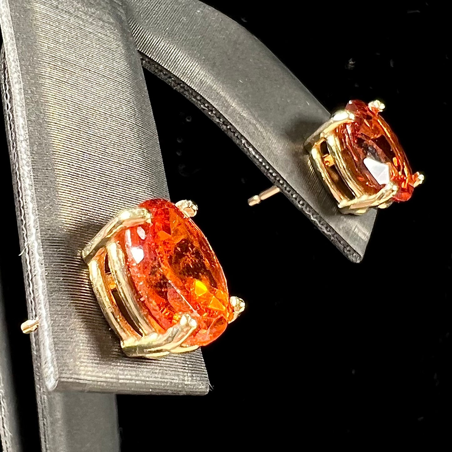 A pair of yellow gold orange hessonite garnet stud earrings.  The garnets are faceted oval cut.