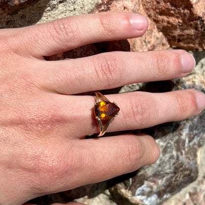 A gold split Euro shank solitaire ring set with an orange pear shape hessonite garnet stone.