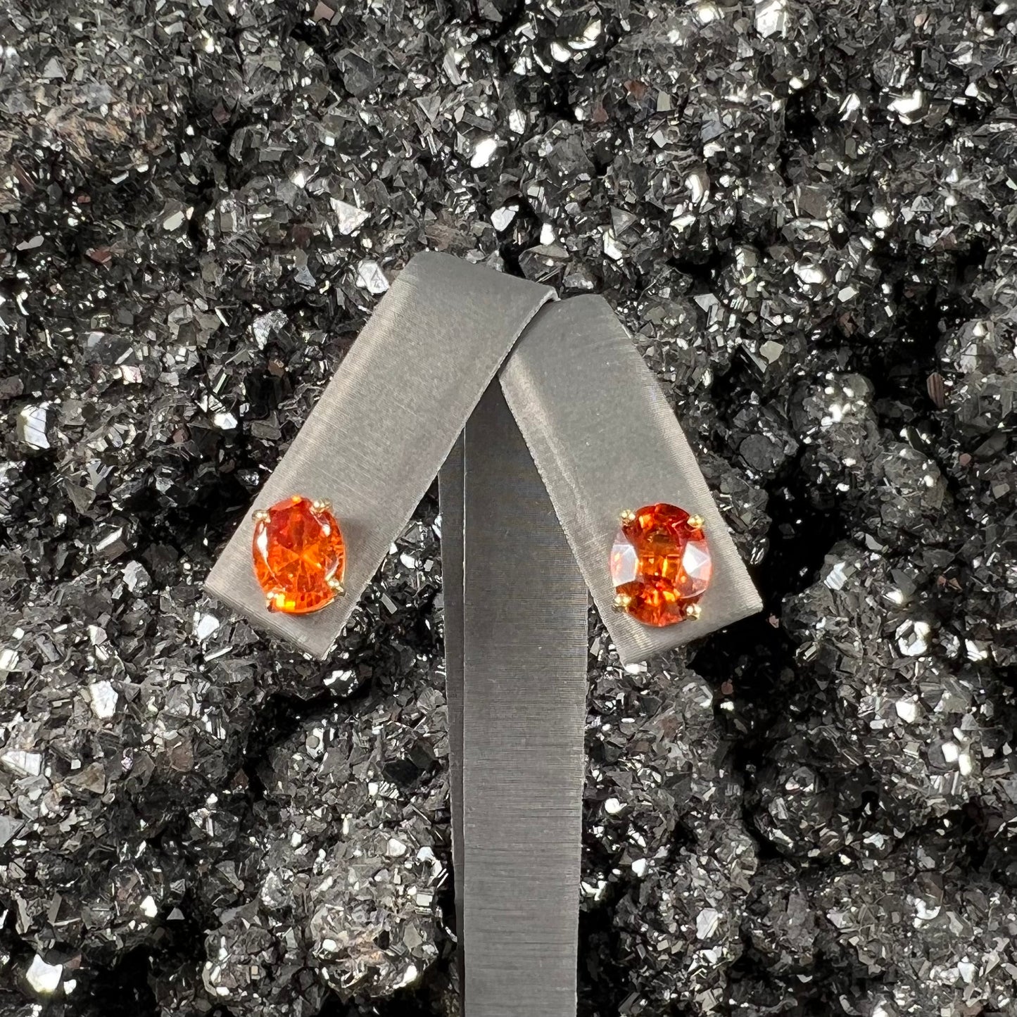 A pair of yellow gold orange hessonite garnet stud earrings.  The garnets are faceted oval cut.