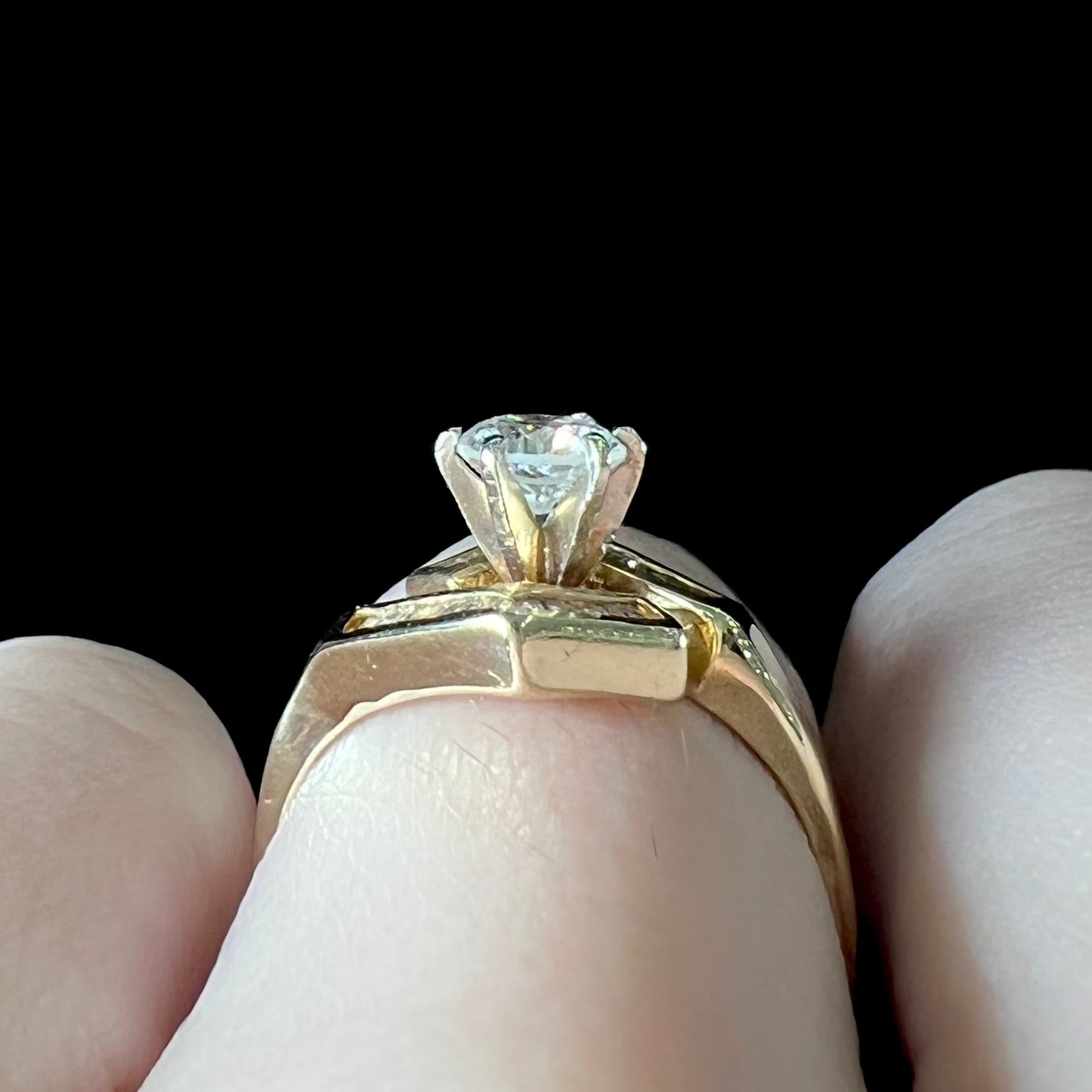 A gold diamond ring set with a round cut center stone with channel set baguette cut accent stones.