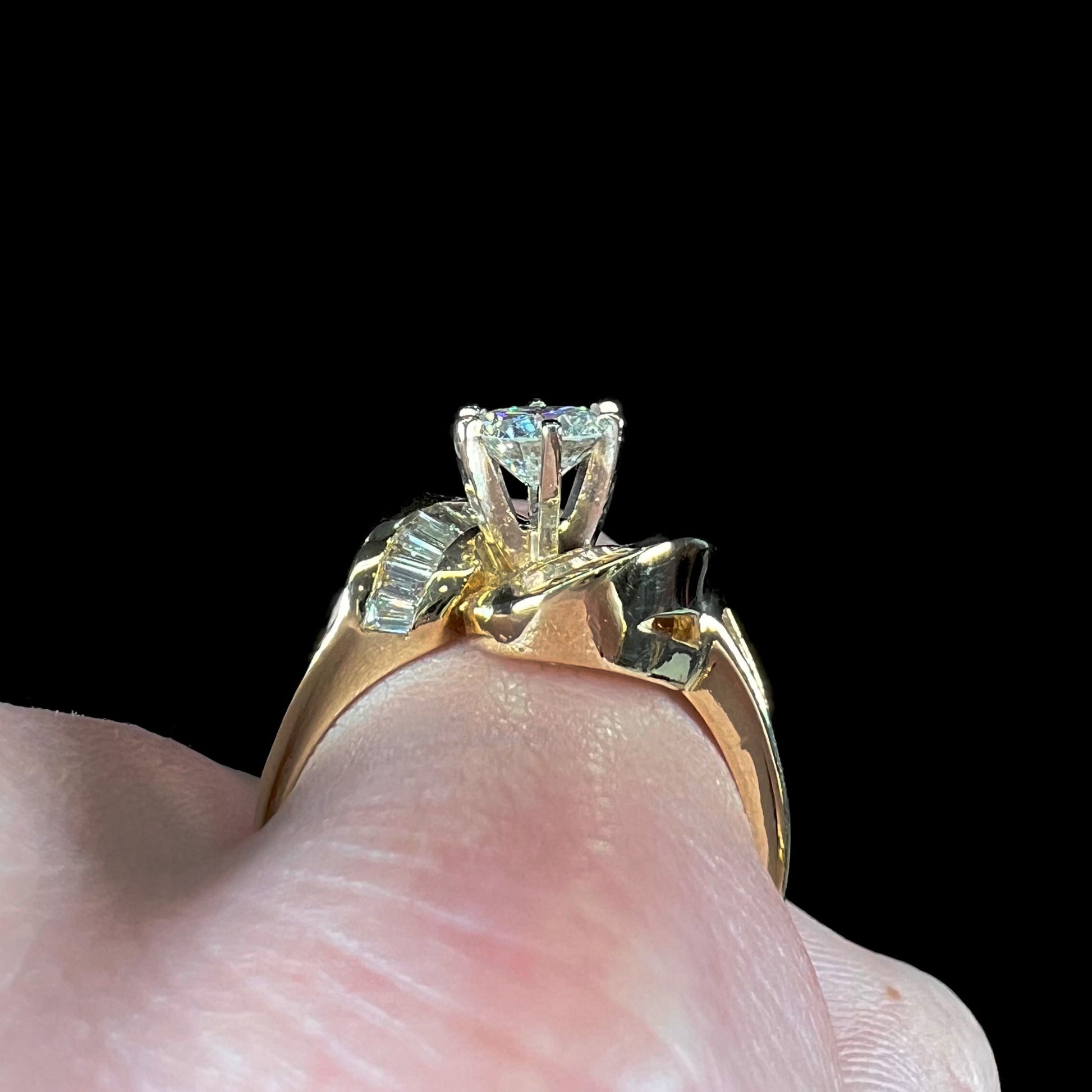 A ladies' yellow gold engagement ring set with a 0.77ct oval cut diamond and baguette cut diamond accents.