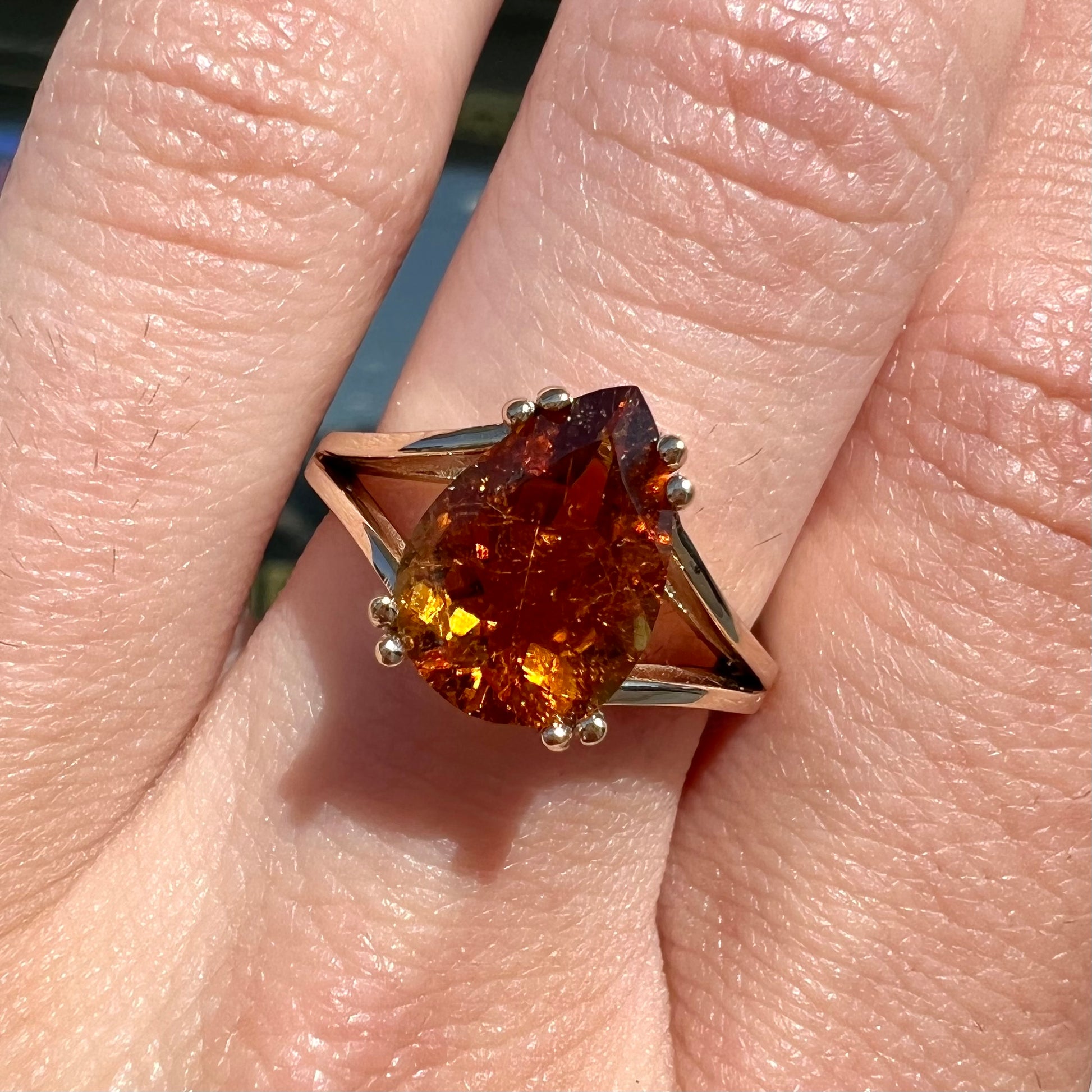 A gold split Euro shank solitaire ring set with an orange pear shape hessonite garnet stone.