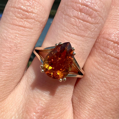 A gold split Euro shank solitaire ring set with an orange pear shape hessonite garnet stone.