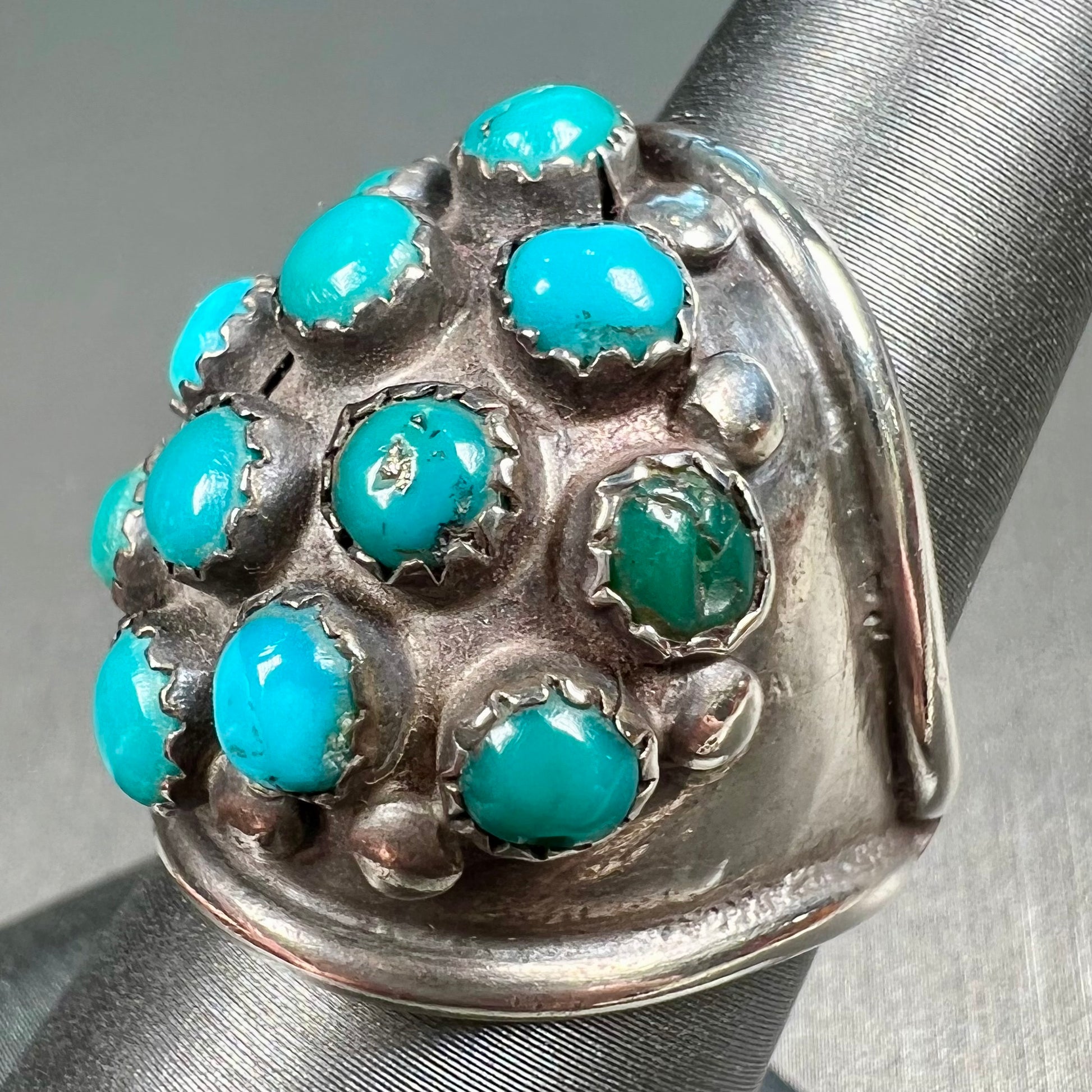 A handmade, unisex Hopi silver ring set with 14 round turquoise cabochons.
