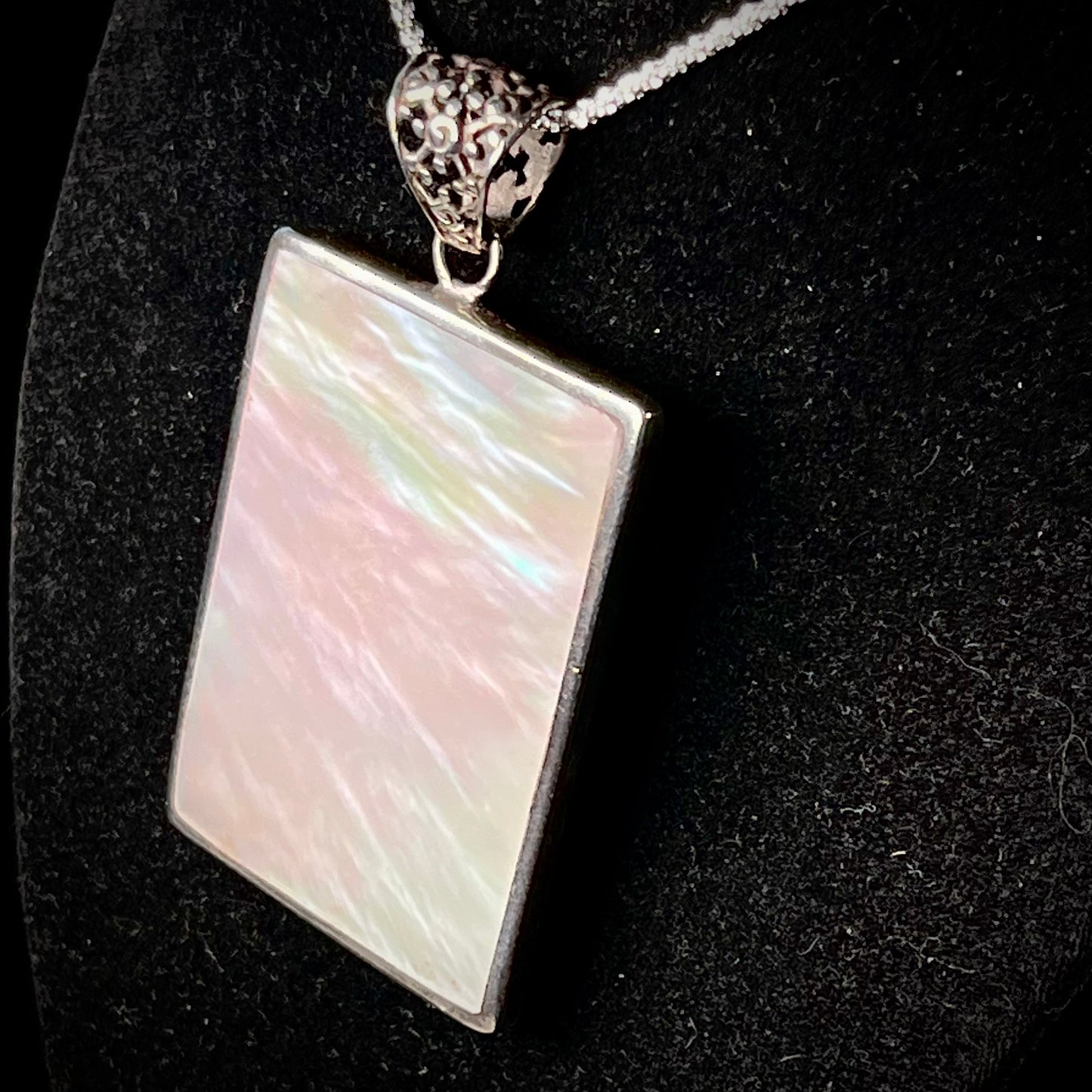 A sterling silver pendant set with rectangular slices of abalone shell and red fossil coral.