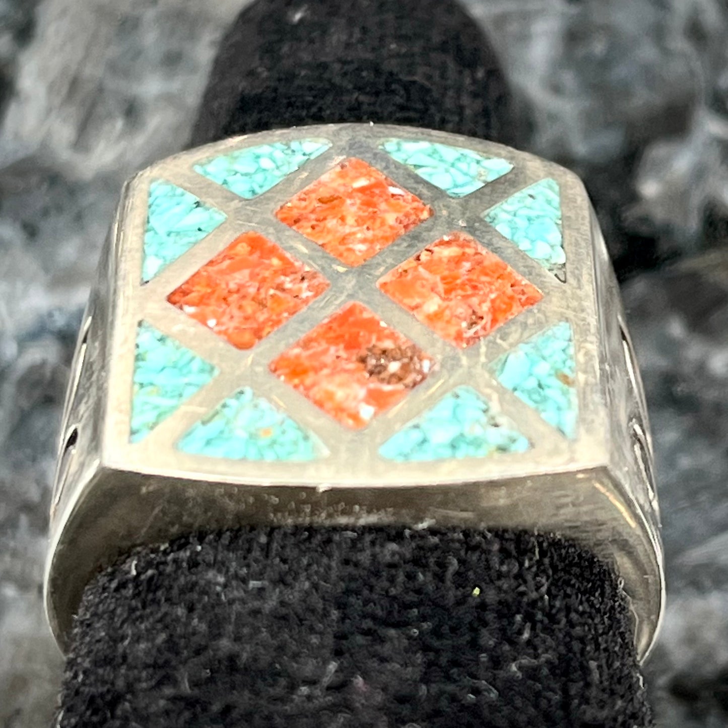 A men's sterling silver inlay ring set with sections of crushed blue turquoise and crushed red coral.