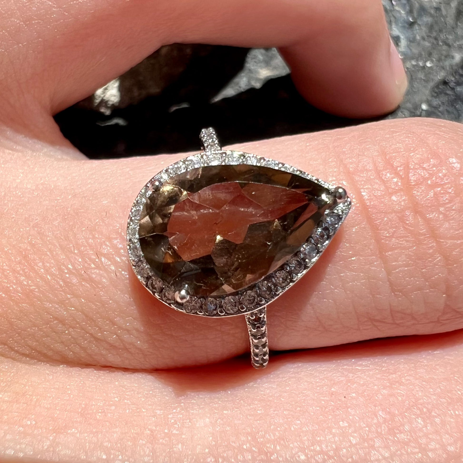 A pear shape smoky quartz set in a sterling silver and CZ halo ring.