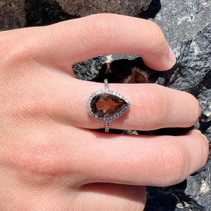 A pear shape smoky quartz set in a sterling silver and CZ halo ring.