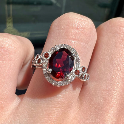 A silver garnet and CZ halo ring.  The center stone is a red almandine garnet, and the side garnets are orange.