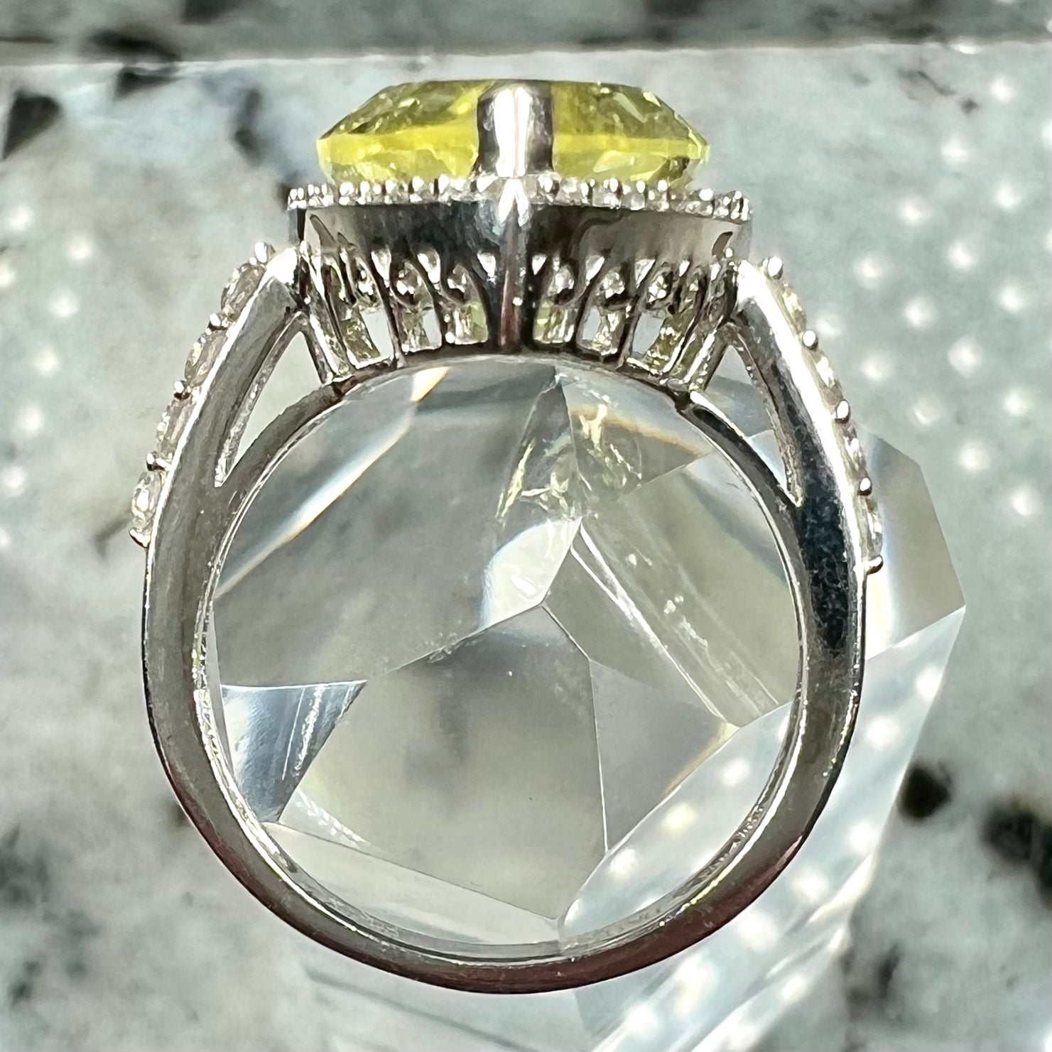 A pear shape lemon quartz set in a sterling silver and white topaz halo ring.