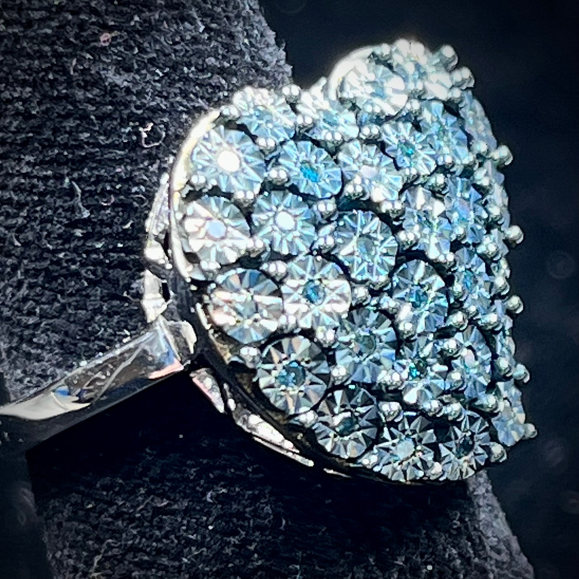 A sterling silver heart ring set with blue diamonds.