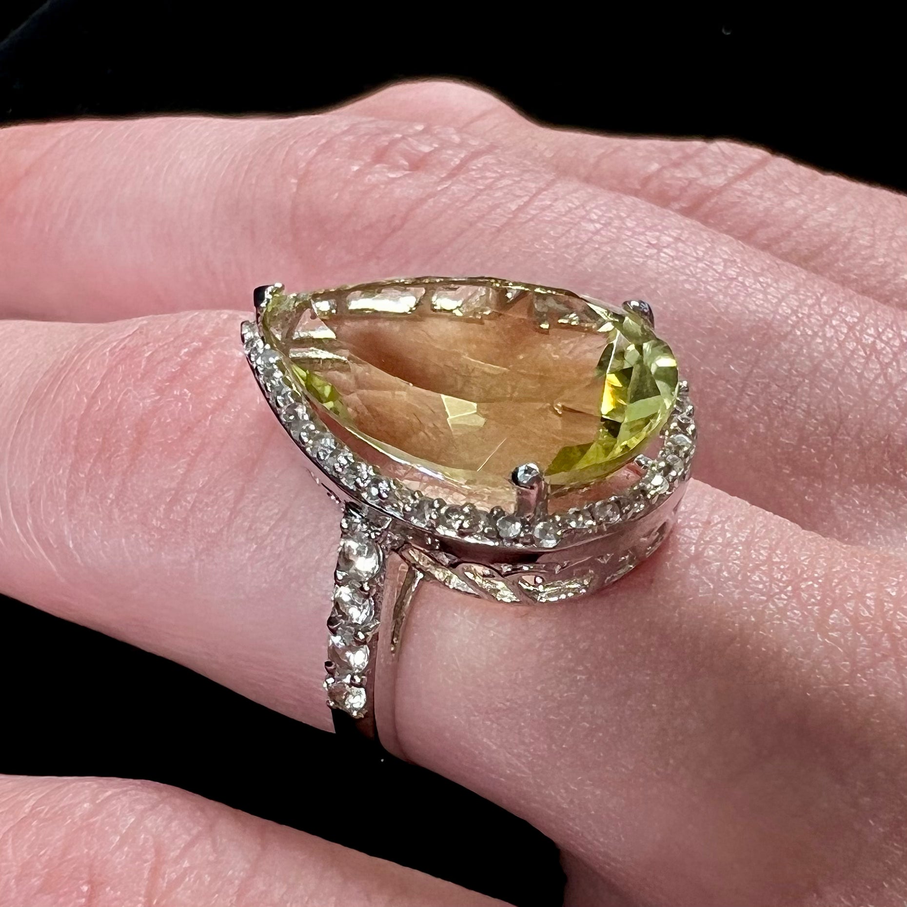 A pear shape lemon quartz set in a sterling silver and white topaz halo ring.