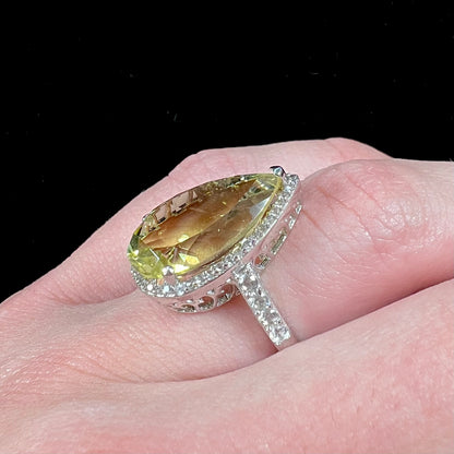 A pear shape lemon quartz set in a sterling silver and white topaz halo ring.