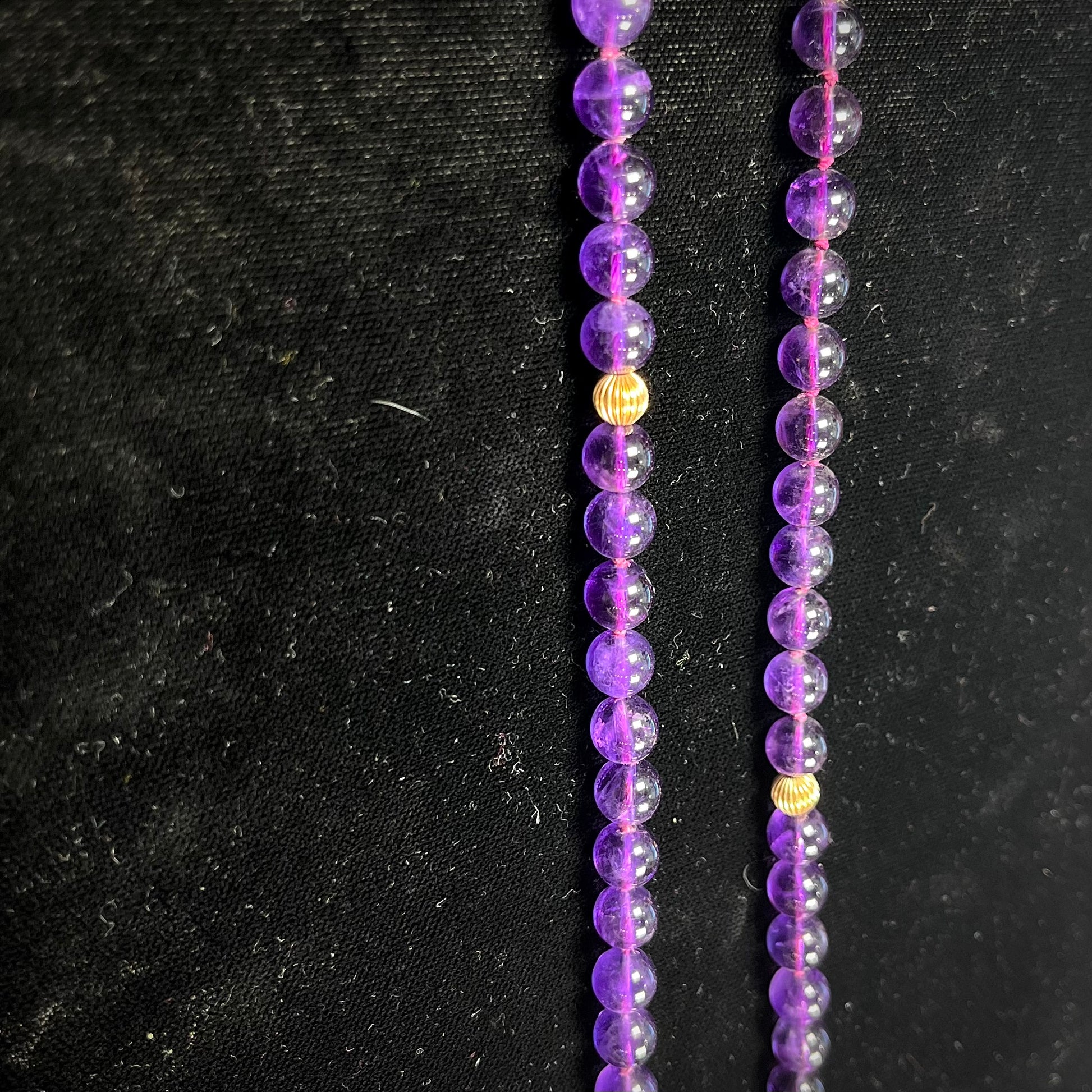 A beaded necklace made with round amethyst and 14k yellow gold beads.