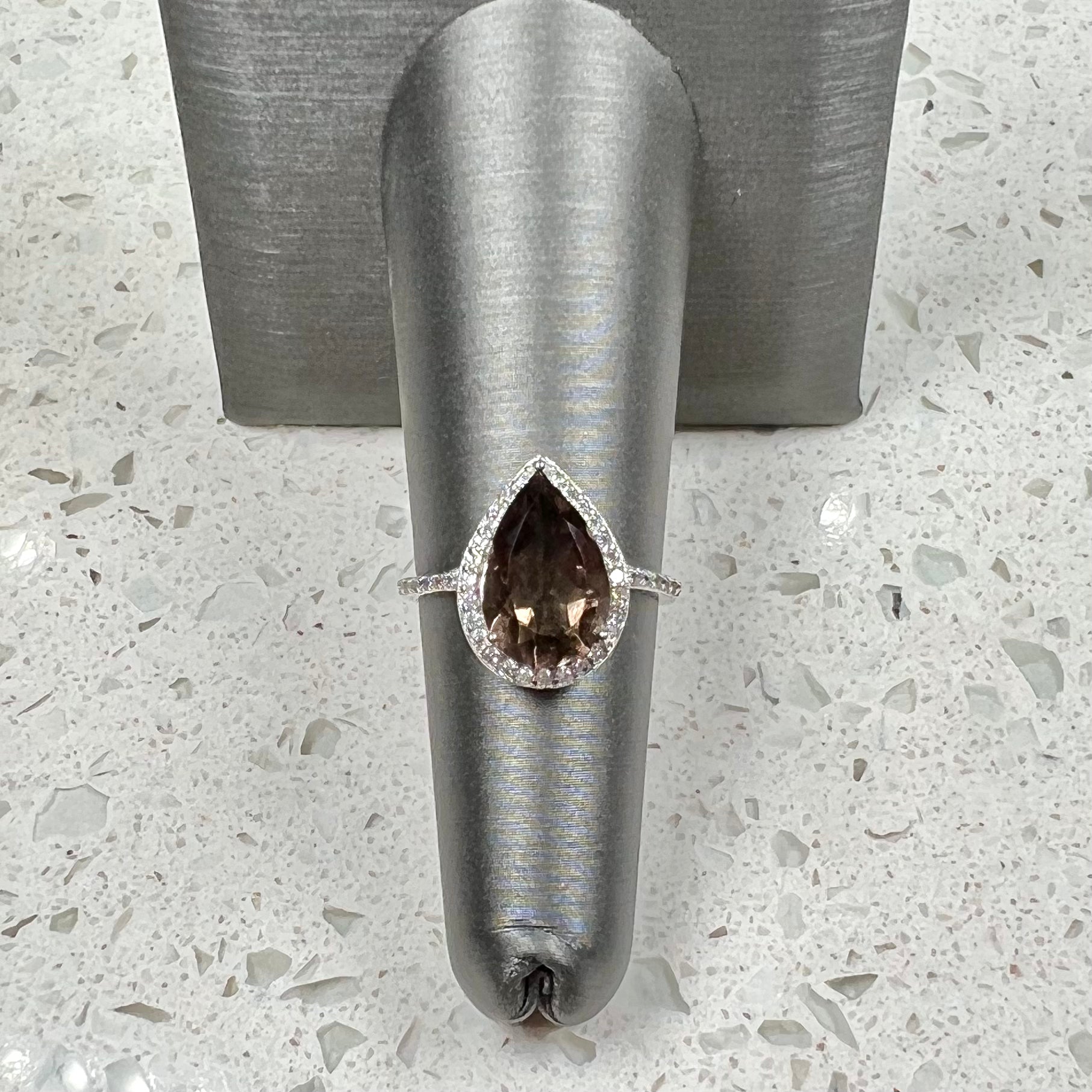 A pear shape smoky quartz set in a sterling silver and CZ halo ring.