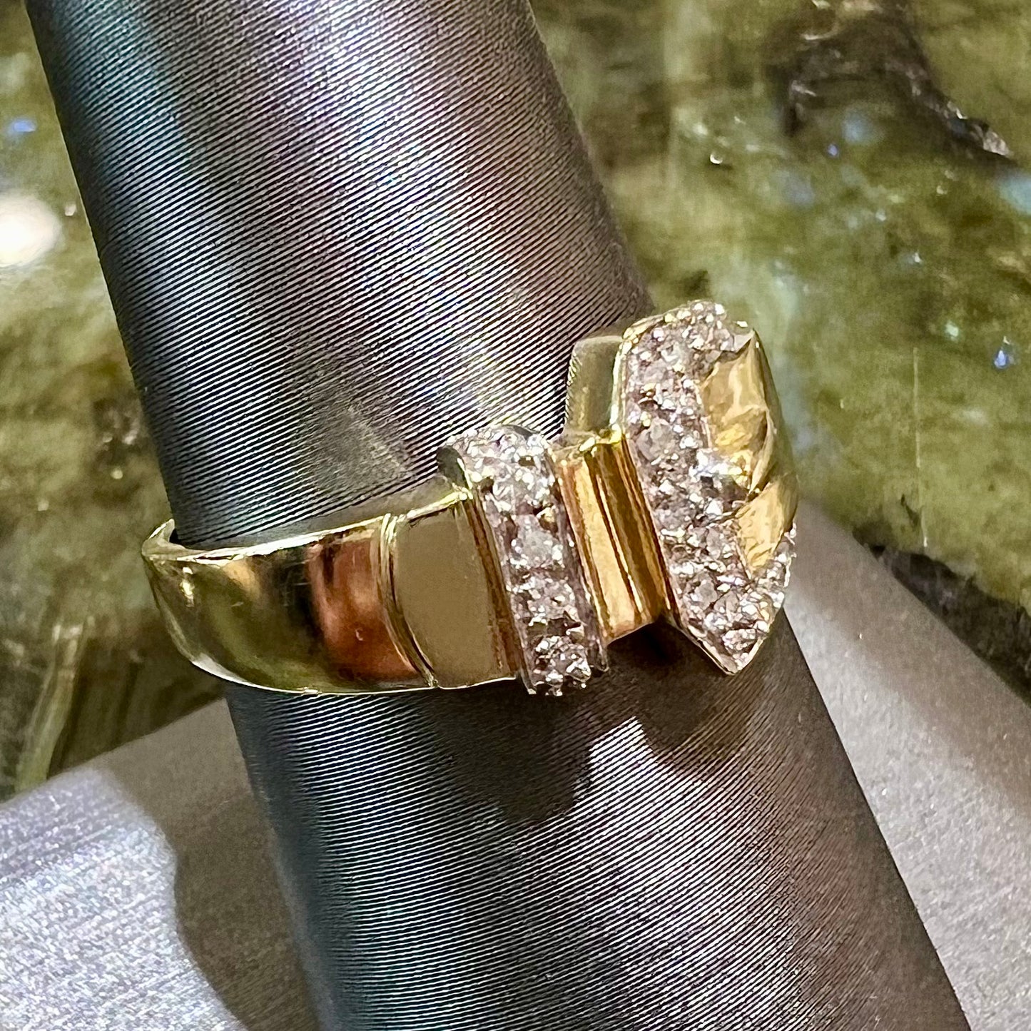 A yellow gold buckle ring set with round diamonds in the buckle.