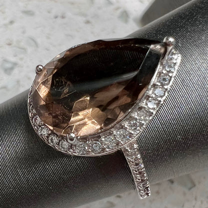 A pear shape smoky quartz set in a sterling silver and CZ halo ring.