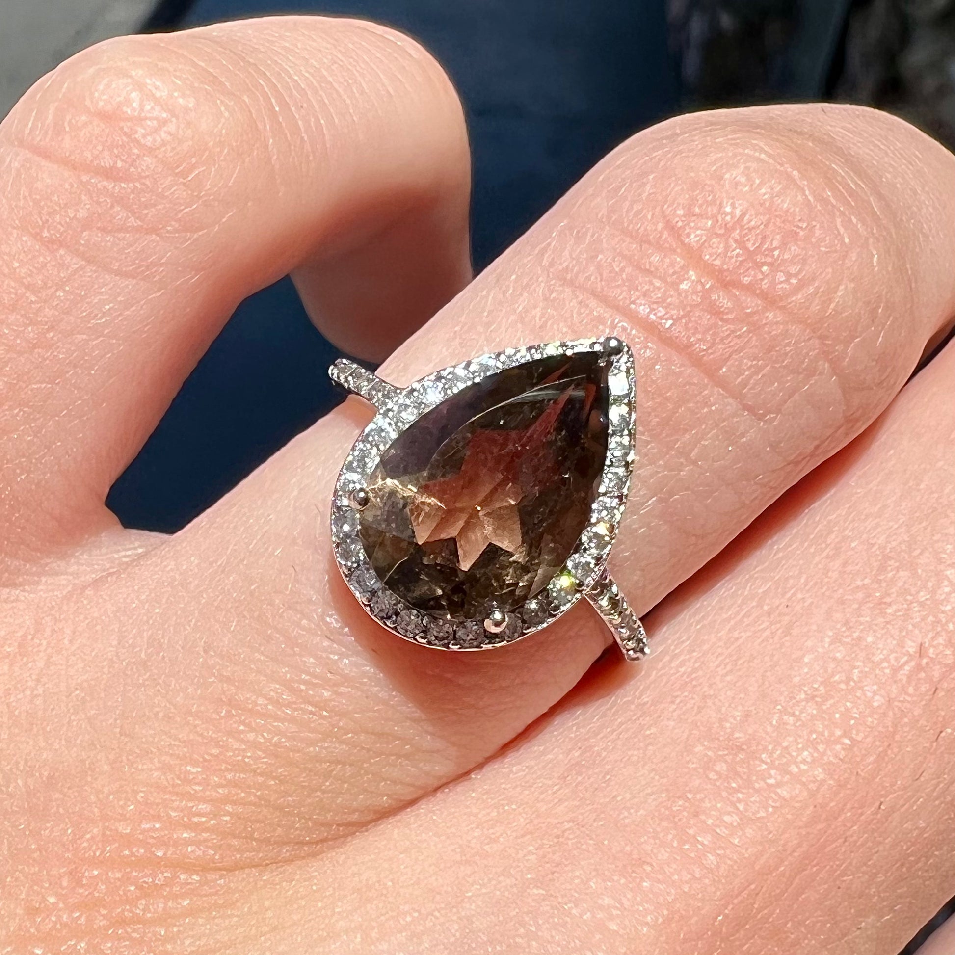 A pear shape smoky quartz set in a sterling silver and CZ halo ring.