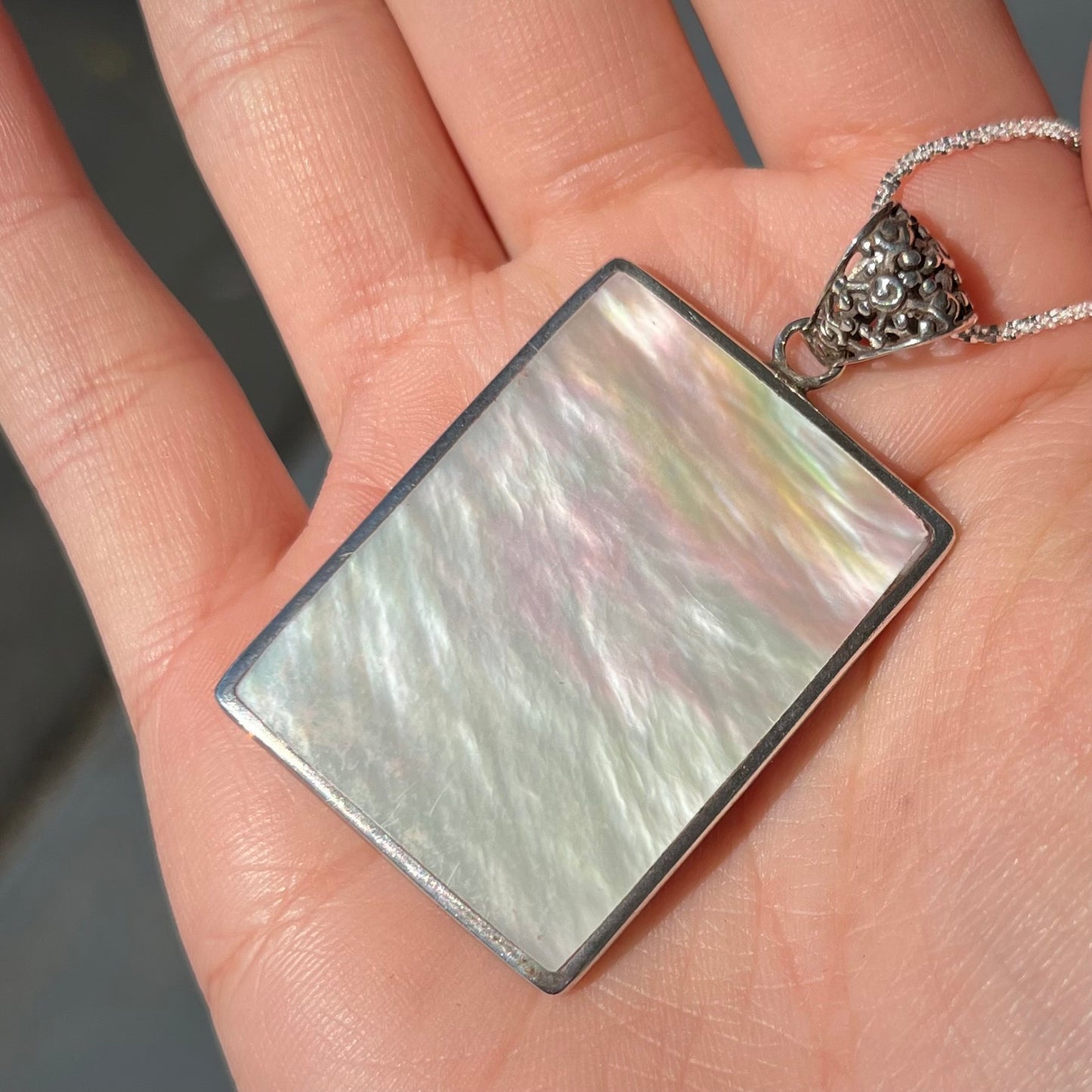 A sterling silver pendant set with rectangular slices of abalone shell and red fossil coral.